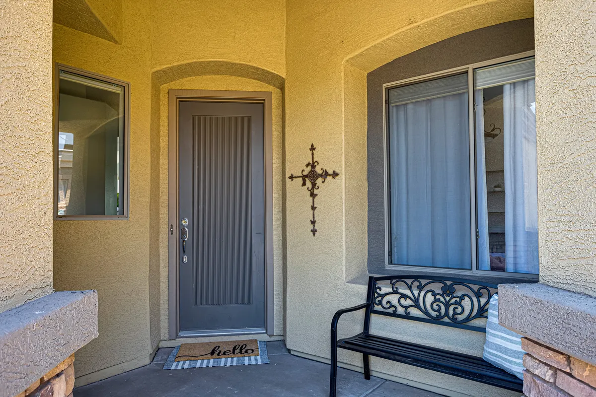 An inviting entryway with a front door, welcome mat, bench for convenience, and decorative touches including a wall cross and bright windows. The scene feels welcoming and practical, illustrating the first moments stepping indoors.