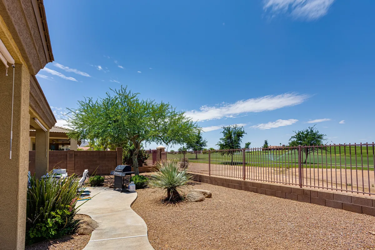 A tranquil backyard with a landscaped pathway, green trees, a fenced yard, and a comfortable seating area. This space offers a peaceful retreat for families, with plenty of room for kids to play, adults to relax, or neighbors to connect.