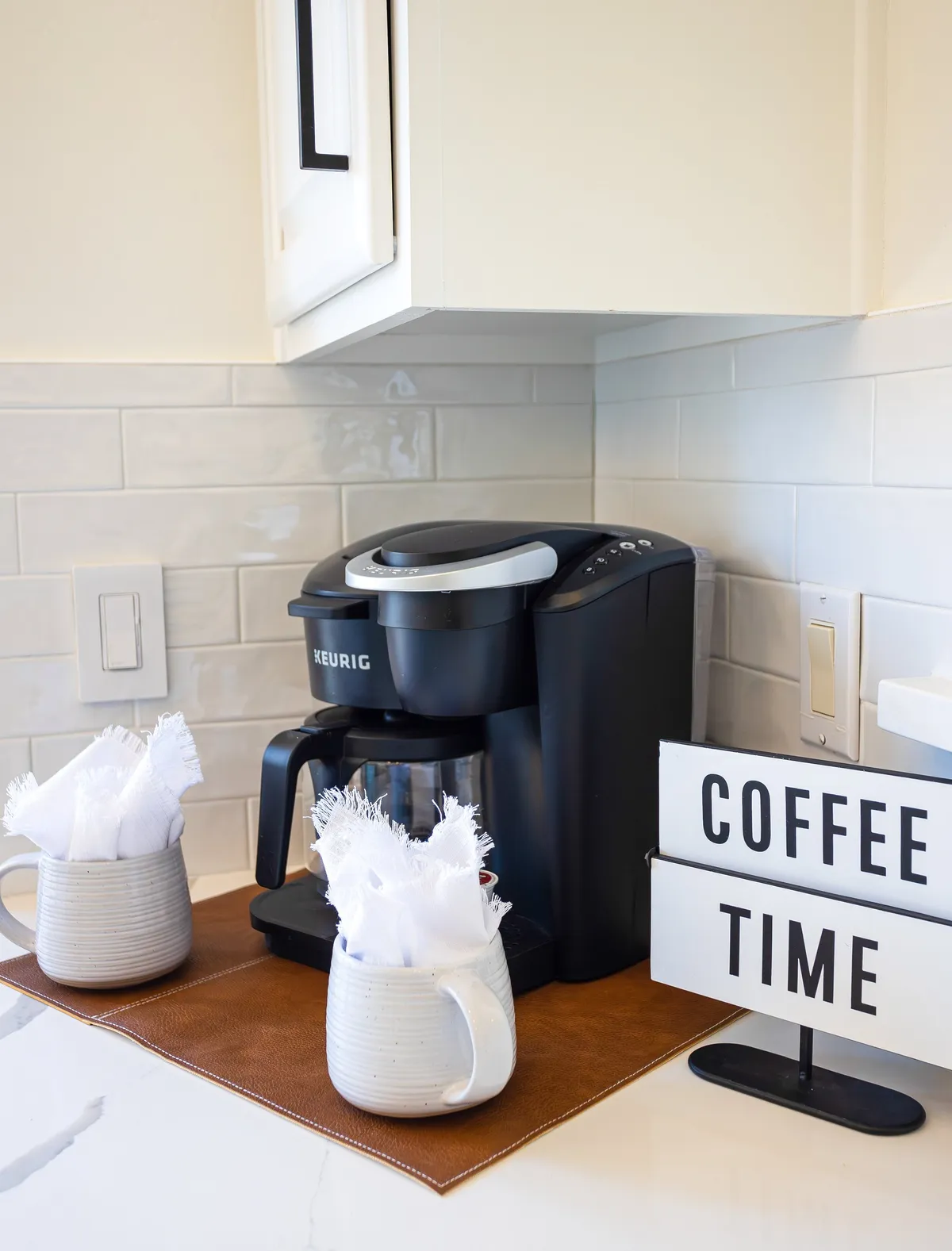 A cozy coffee station with a Keurig, two ceramic mugs, and a 'coffee time' sign, inviting guests to enjoy quiet mornings and establish comforting rituals. The scene is set for relaxed morning routines or socializing over a fresh brew.