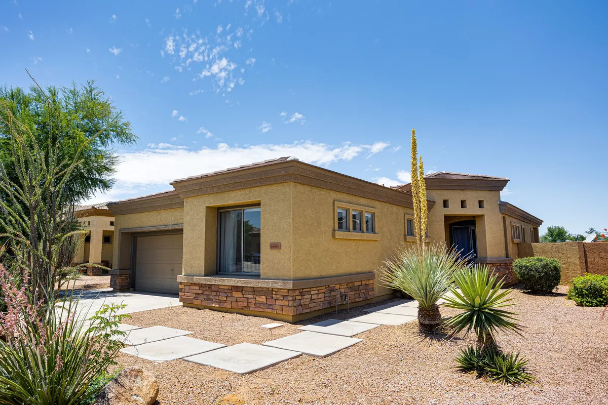 This exterior shot captures the front entrance of the home, framed by large windows and a beautifully landscaped garden. The inviting porch suggests a welcoming entry point, while the surrounding greenery hints at the lush outdoor environment available to residents.